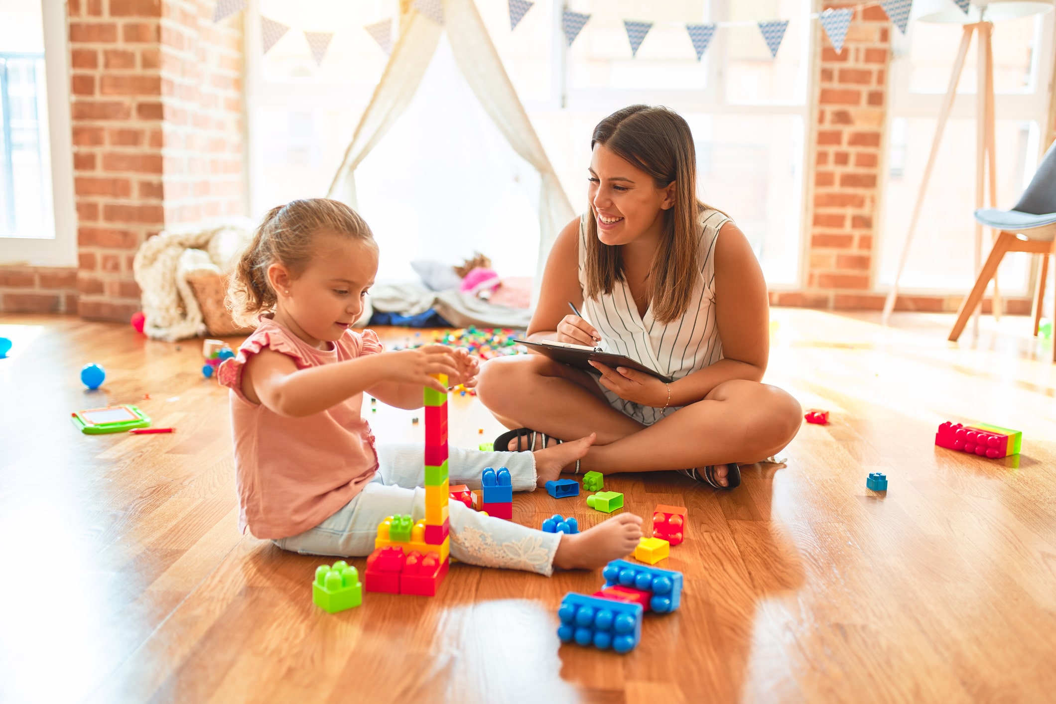 Girl playing with legos and woman talking to her