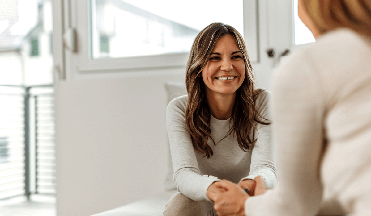 Woman holding another woman's hand and smiling