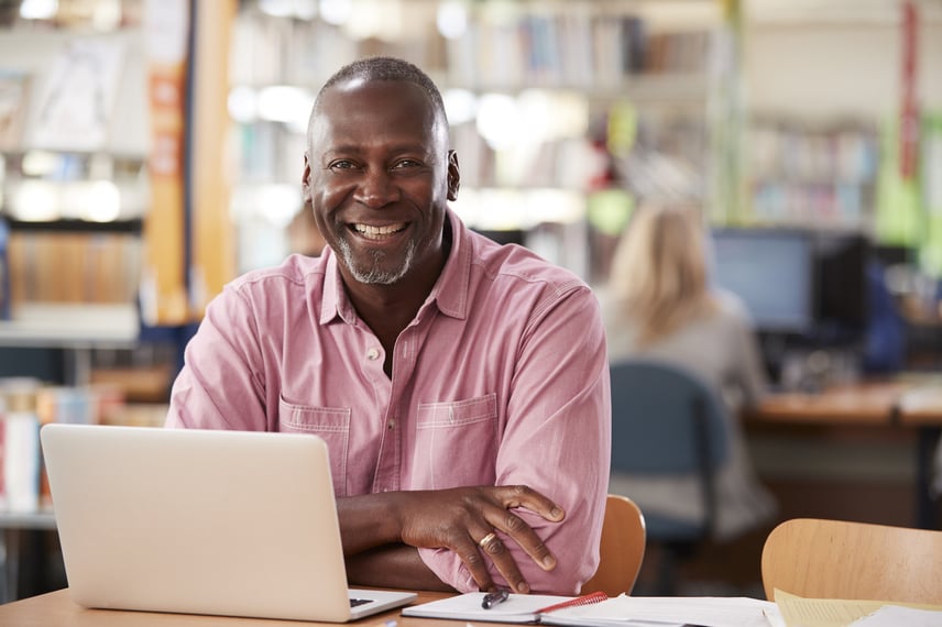 Male Student Using Laptop In Library
