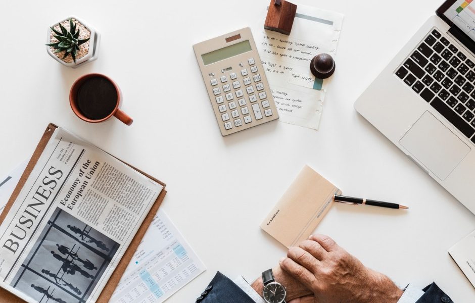 newspaper, calculator and mug on table top