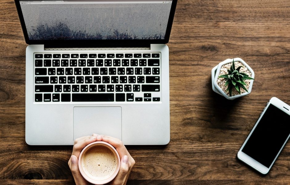 open laptop next to plant and phone