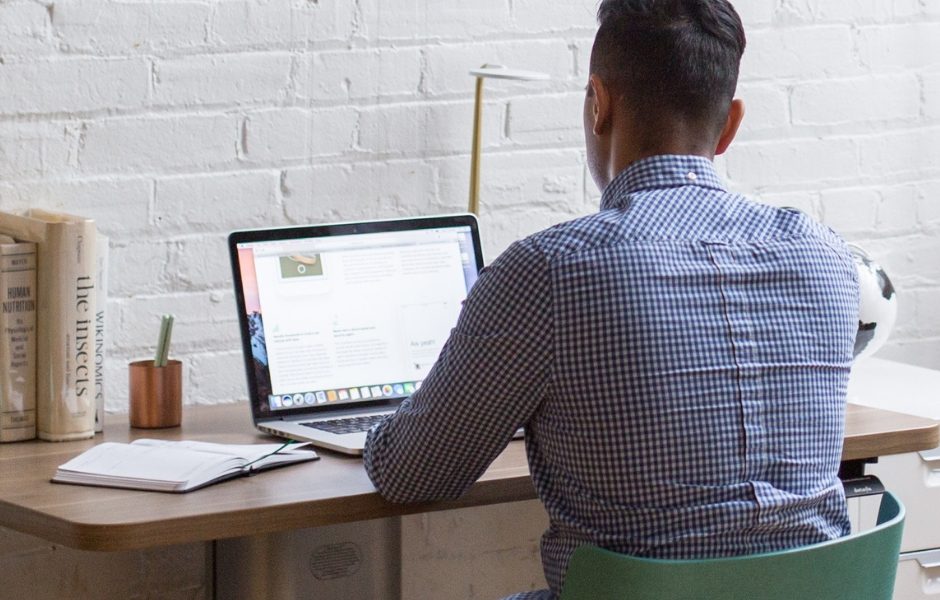 man sitting at a desk on laptop