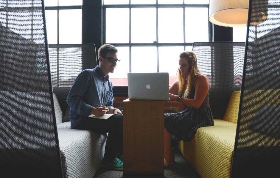 two people sitting around a laptop