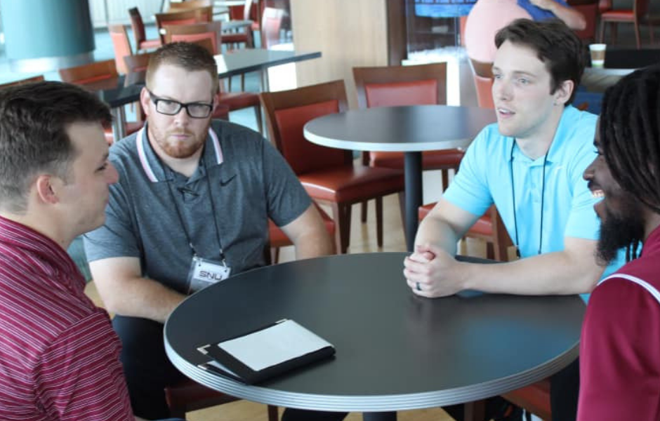 four people sitting at a table talking