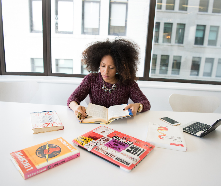 woman sitting at white table with books