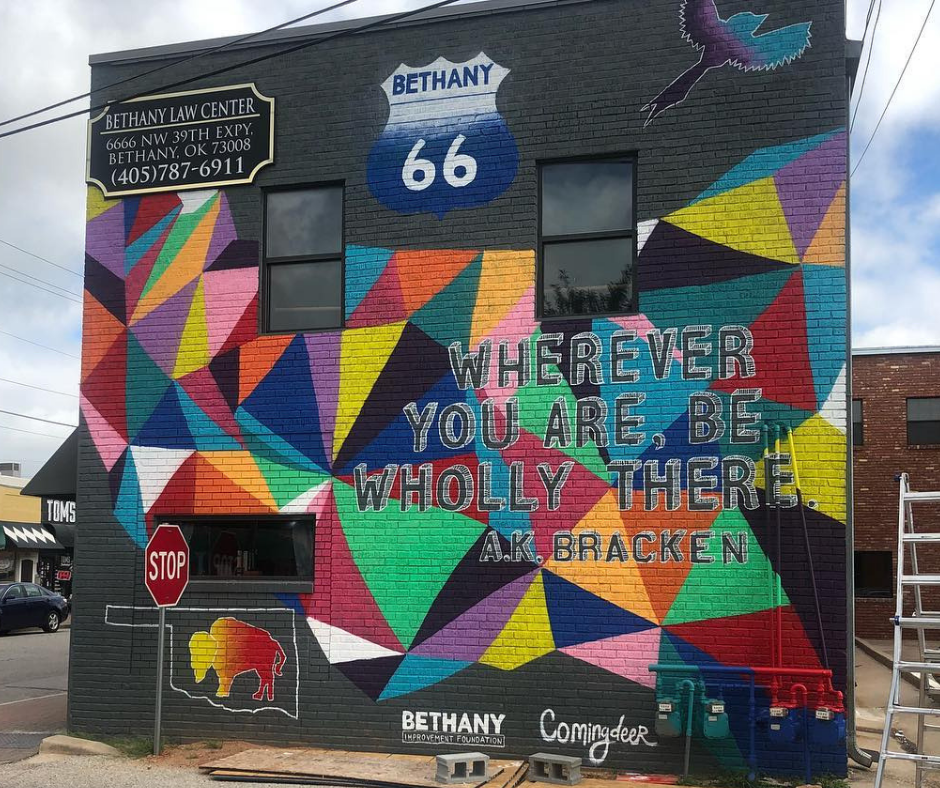 Decorative wall mural outside SNU Campus in Bethany. It says "Wherever you are, be wholly there. AK Bracken"