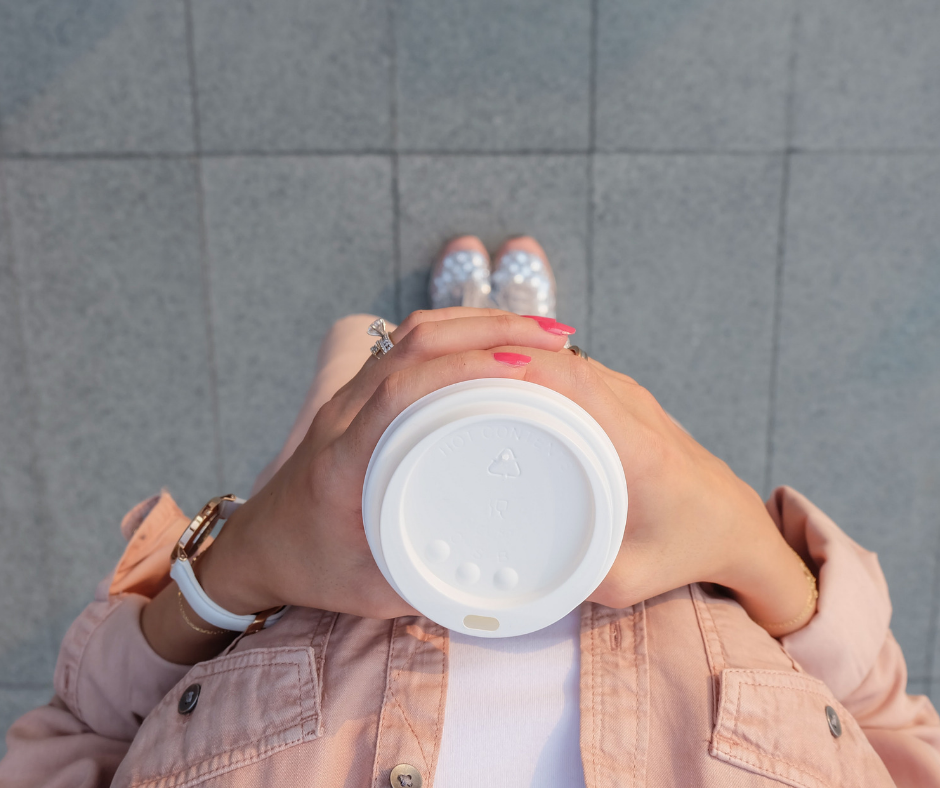 woman holding cup on sidewalk