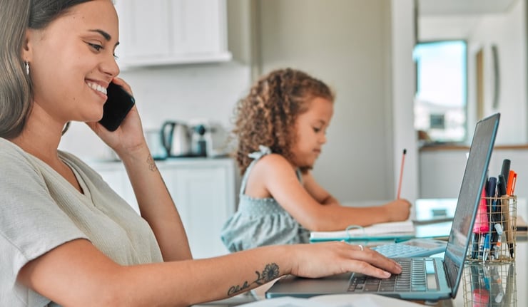 A mom working on her college assignments while her daughter does homework in the background.