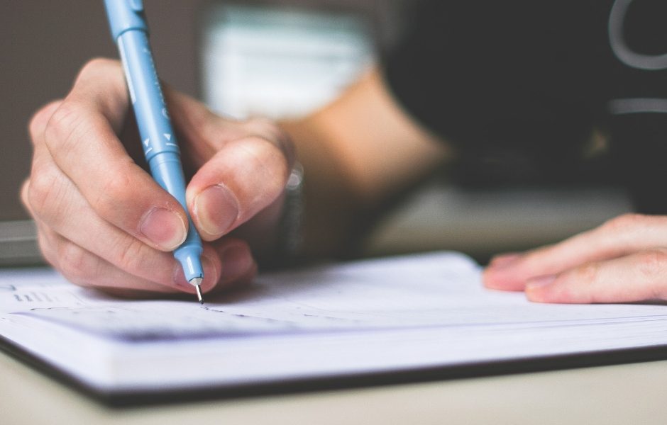 person writing on paper with pen