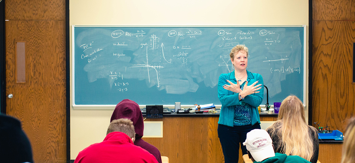 professor teach math in front of a chalk board